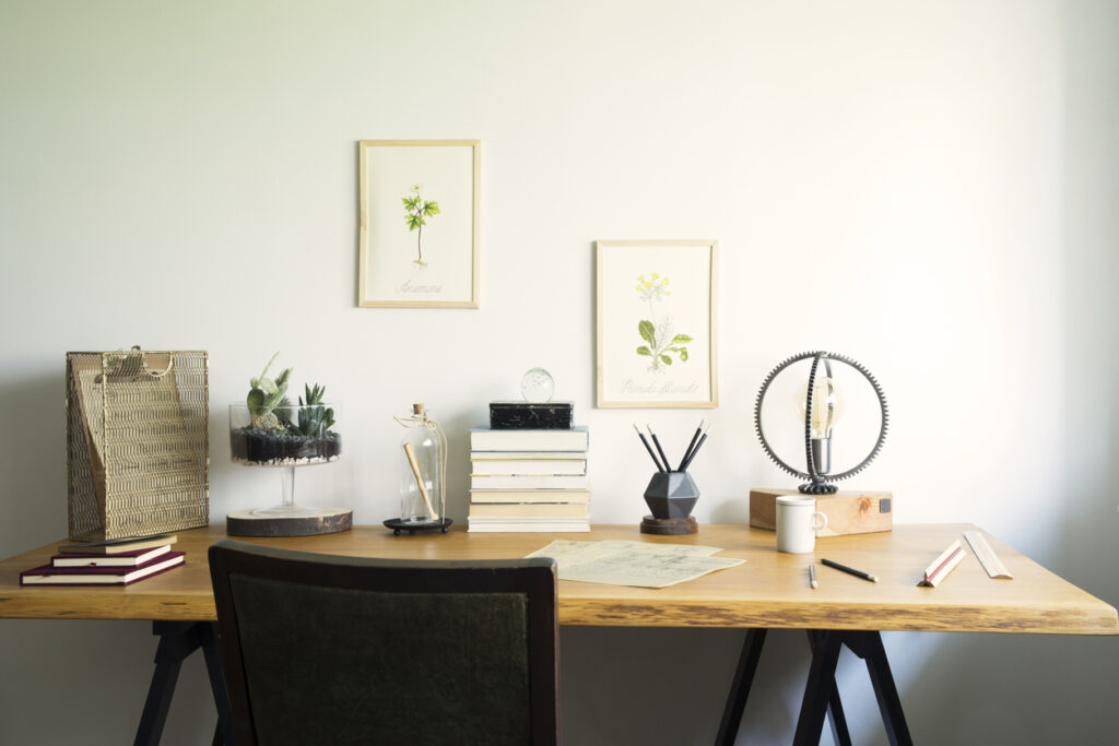 一人暮らしの部屋に置かれた木製デスクと観葉植物のあるシンプルな在宅ワークスペース
