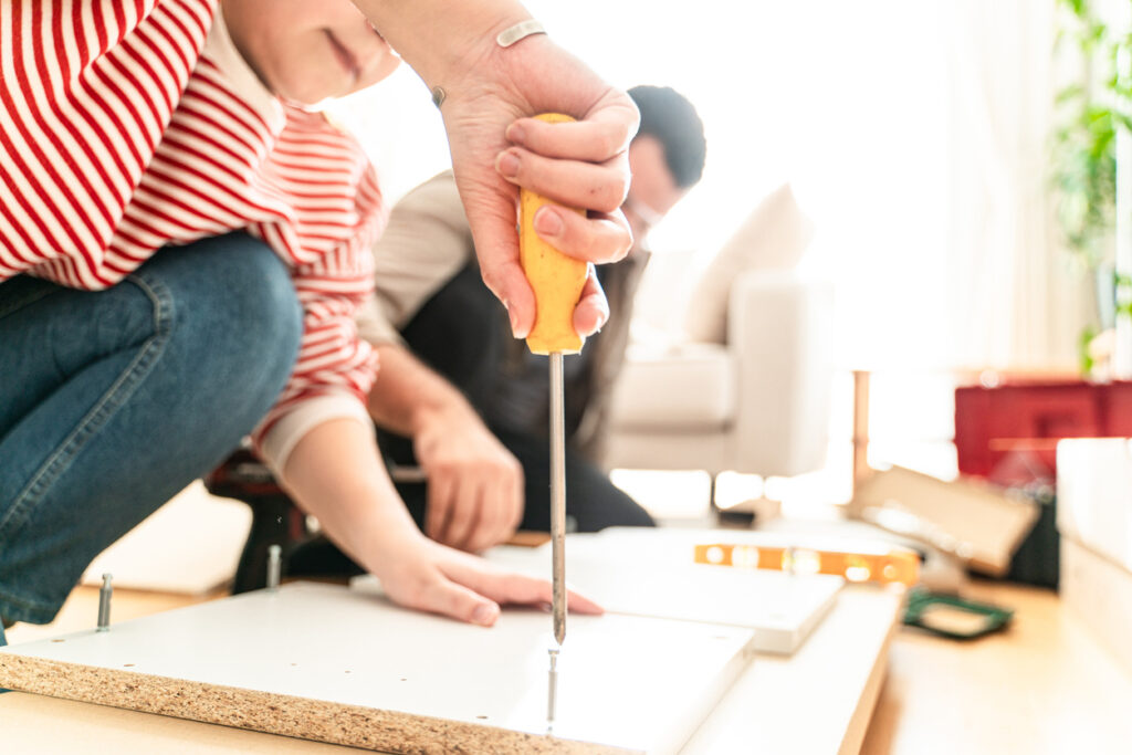 明るい室内で家具の組み立て作業を行う手元。ドライバーを使って丁寧にネジを締めている様子