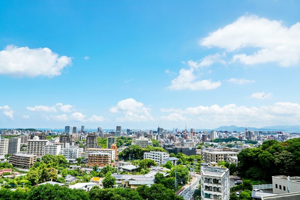 青空の下に広がる都市風景。中高層の建物や緑が入り混じったバランスの良い市街地の景観