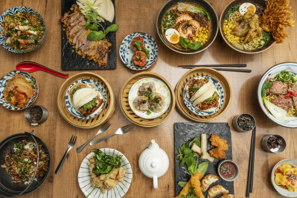 ひとり暮らしでも楽しめる、本格アジアン料理を並べた食卓。餃子や小籠包、ラーメン、バオ、キムチなどが多彩な器に盛り付けられている。
